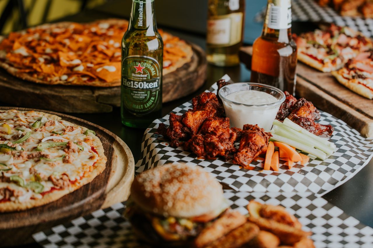 Mouth-watering pizza, beer, and chicken wings plated for a delightful dining experience.